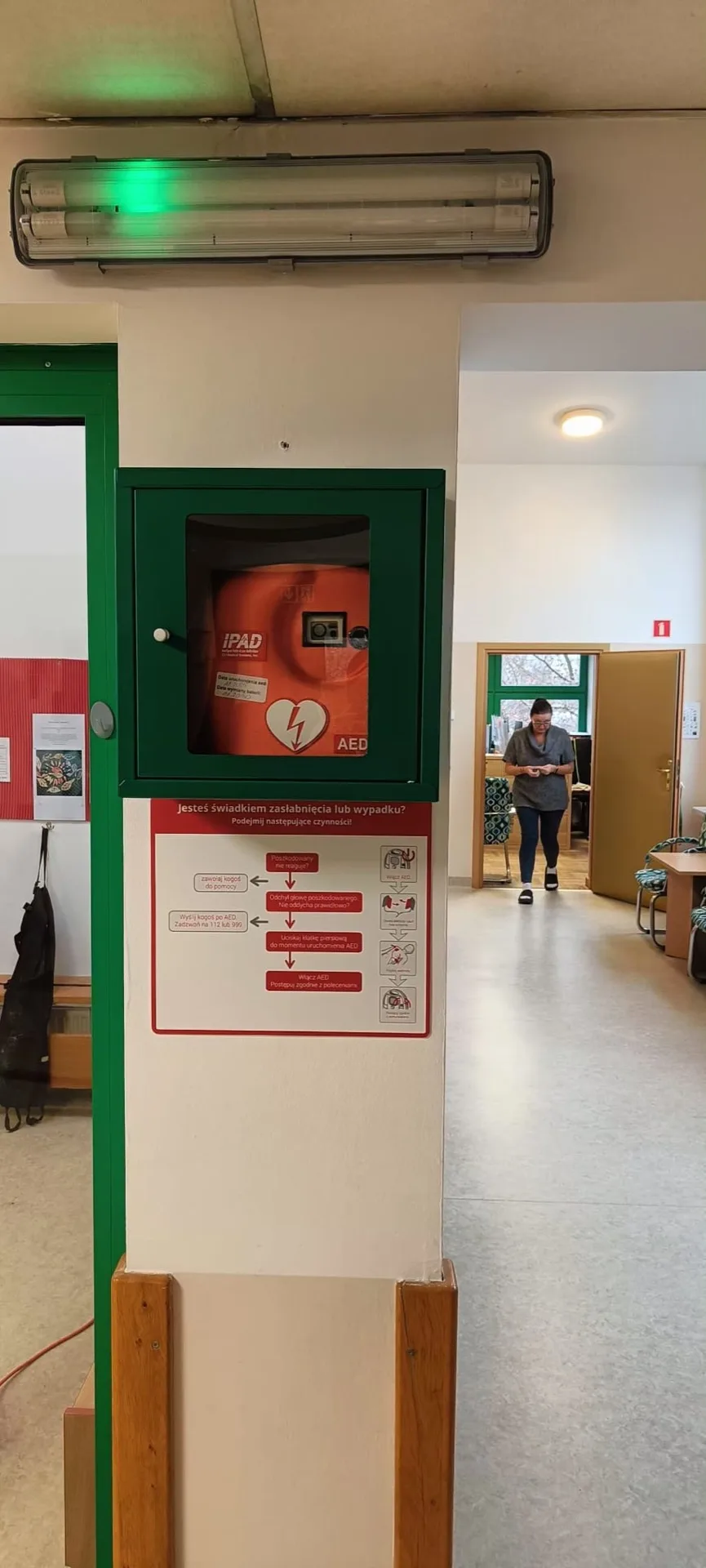 Defibrylator w szafce z oznakowaniem na korytarzu budynku miejskiego w Warszawie